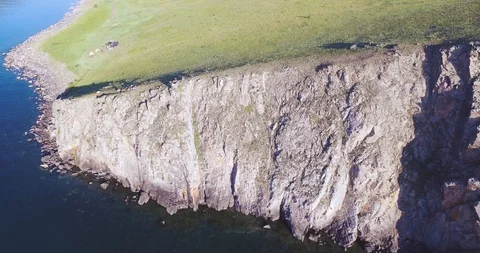 Circular flight over the rocky coast of a Baikal lake. There is a reflection of Stock Footage 93307550
