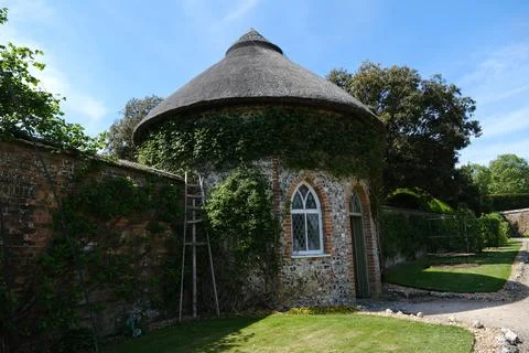 The circular flint Apple Store with thatched roof in West Dean Gardens. Stock Photos