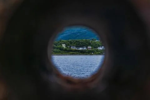 Circular framed view of coastal settlement through stone aperture, Norway fjo Stock Photos