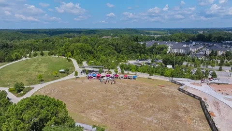 Circular grassy amphitheater surrounds small outdoor gathering with colorful Stock Footage 344153077