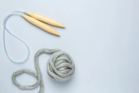 Circular knitting needles and thick grey yarn on blue background Stock Photos