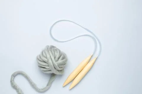 Circular knitting needles and thick grey yarn on blue background Stock Photos