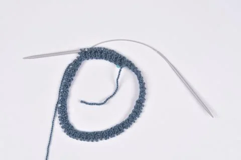 Circular knitting process with blue yarn on a white background Stock Photos