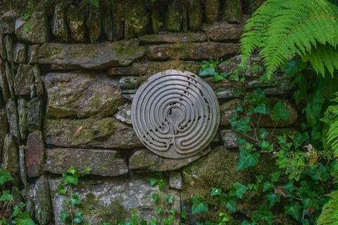 Circular labyrinth carving on moss covered stone wall near Lansallos Stock Photos