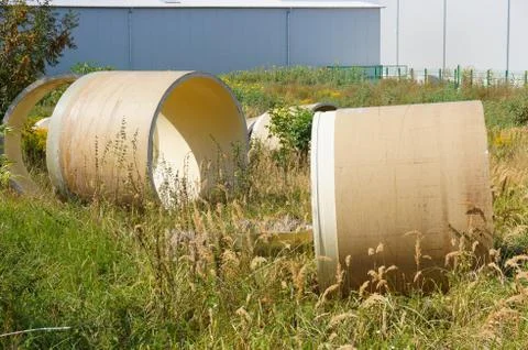 Circular objects on a field of grass surrounded by trees behind the wall Stock Photos