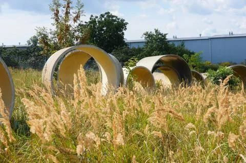 Circular objects on a field of grass surrounded by trees behind the wall Stock Photos
