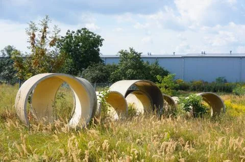 Circular objects on a field of grass surrounded by trees behind the wall Stock Photos