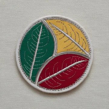 A circular patch with three overlapping leaf patterns in green, yellow, and.. Stock Photos