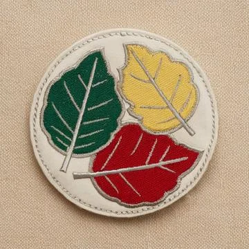 A circular patch with three overlapping leaf patterns in green, yellow, and.. Stock Photos