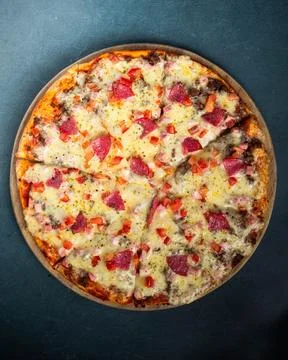 Circular pizza rests on dark surface Фото