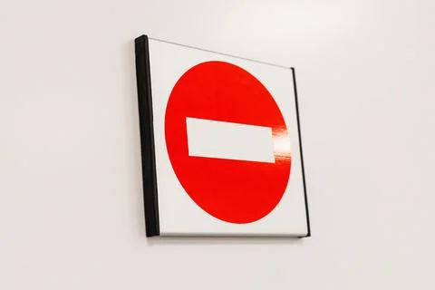 A circular red no entry sign with a white horizontal stripe is mounted on a.. Stock Photos