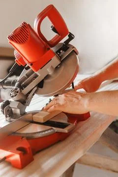 Circular saw in action as a carpenter skillfully cuts wooden planks. Hands hold Stock Photos