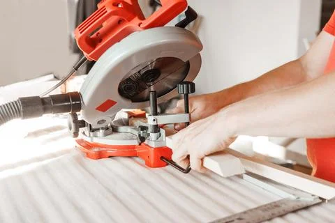 Circular saw in action as a carpenter skillfully cuts wooden planks. Hands hold Stock Photos