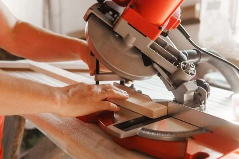 Circular saw in action as a carpenter skillfully cuts wooden planks. Hands hold Foto stock