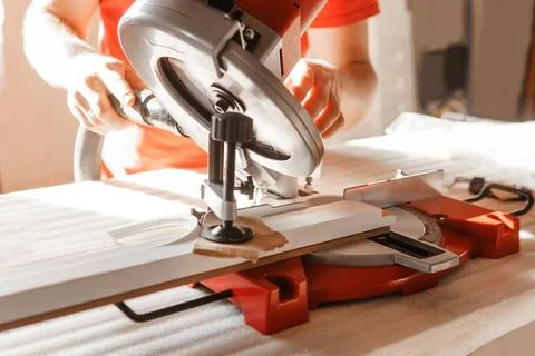 Circular saw in action as a carpenter skillfully cuts wooden planks. Hands hold Stock Photos
