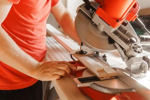 Circular saw in action as a carpenter skillfully cuts wooden planks. Hands hold Stock Photos