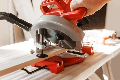 Circular saw in action as a carpenter skillfully cuts wooden planks. Hands hold Foto stock