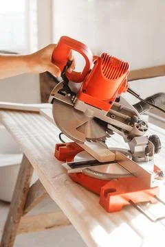 Circular saw in action as a carpenter skillfully cuts wooden planks. Hands hold Stock Photos