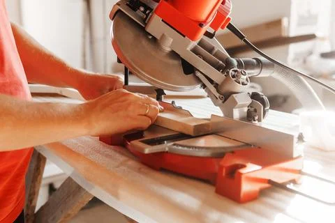Circular saw in action as a carpenter skillfully cuts wooden planks. Hands hold Stock Photos