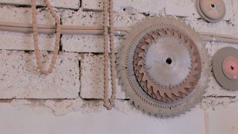 Circular saw blade hanging on the brick wall with chain and buffing disc. Stock-Footage 85588673