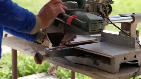 Circular saw cutting wood plank in concentrated and precise outdoor grassy area Stock Footage 344874377