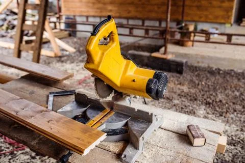 Circular saw laid on table, stack of wood behind it Stock-Fotos