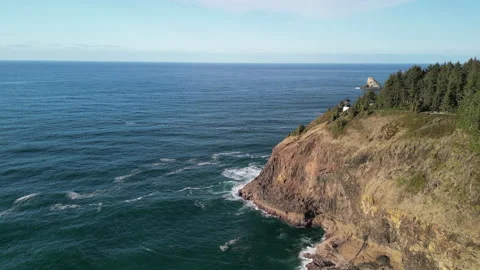 Circular Shot Rotating Around Lighthouse Perched on Cliff with Ocean All Around 库存影片 228751590