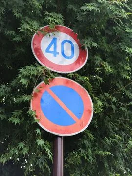 Circular signs mount on a pole, set against green foliage Stock Photos