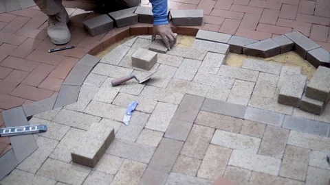 Circular steadicam shot of brick paver artisan fitting bricks into a two-tone Stock Footage 80513832