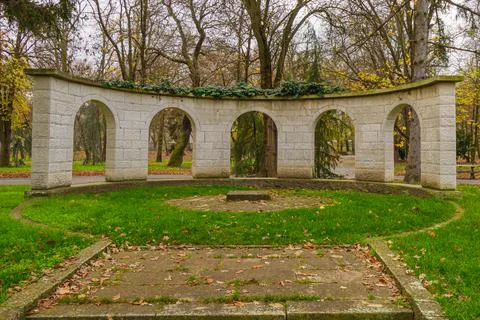 Circular stone structure surrounded by trees in a park during autumn with f.. Stock Photos