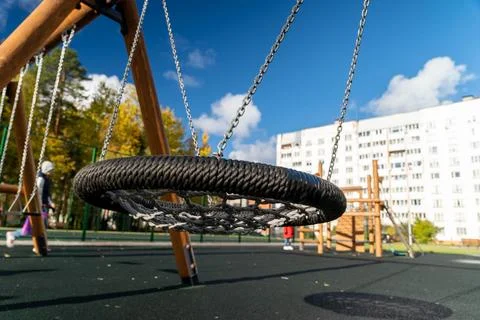 Circular swing made of durable material hangs from wooden frame in a vibrant 库存照片