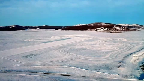 Circular Vehicle Tracks Pattern Across an Empty Snowfield Vídeo Stock 345011506