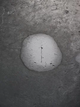 Circular wet patch on concrete floor with central crack and gritty texture mood Stock Photos
