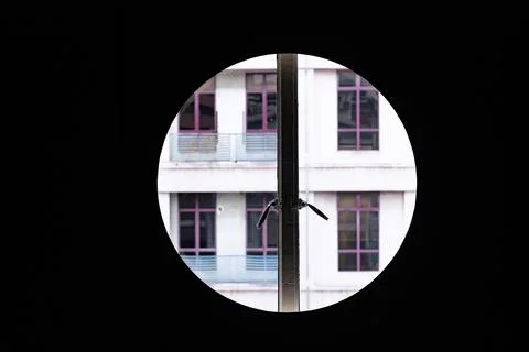 Circular window framing a modern apartment building facade with symmetrical w Stock Photos