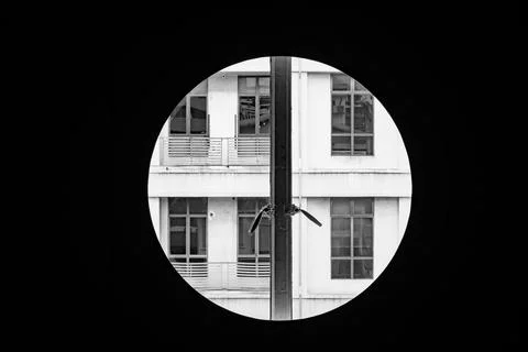 Circular window framing a modern apartment building facade with symmetrical w Stock Photos