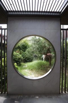 Circular window view of a lush green garden in a modern architectural setting Stock Photos