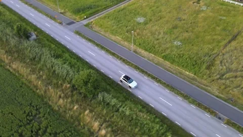 Circulating above a moving silver colored sports car on the countryside Stock Footage 147083989