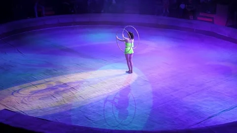 A circus artist performs in the circus arena with a lot of hula hoops, creates a Stock Footage 168922608