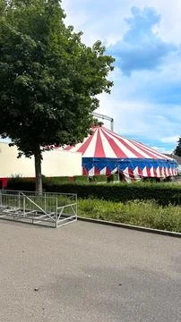 Circus Tent Glimpsed Through Trees Along a Paved Footpath on a Sunny Day Stock Photos
