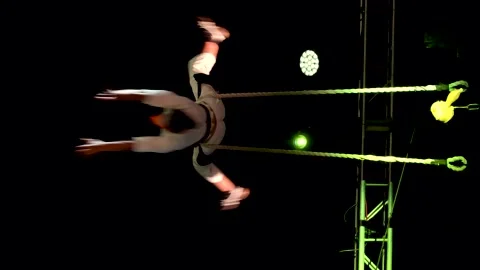 Circus tightrope walker holding on to two ropes while doing a show climbing up 스톡 동영상 227779247