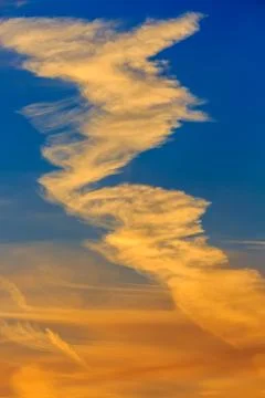 Cirrus cloud infront of a blue and orange sky Stock Photos