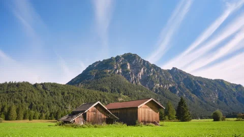 Cirrus radiatus clouds over a mountain and farm sheds in Tyrol, Austria. Stock Footage 146271234