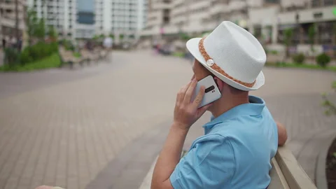 Citizen talking on a mobile phone while sitting on a bench, camera tracking Stock Footage 153871566