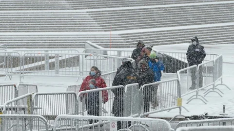 Citizens walking by security guards during snowfall to go test for covid-19 Stock Footage 126993877