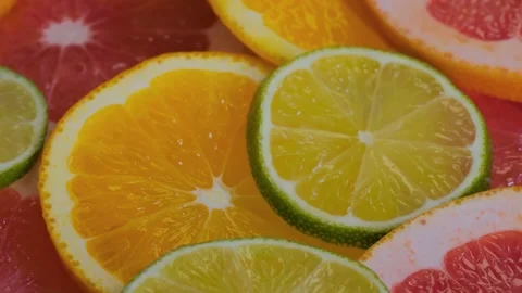 Citrus fruit slices - grapefruit, orange, lemon and lime on rotating surface Stock Footage 233843077