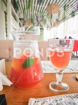 Citrus lemonade on the table, orange cool summer drink in the decanter and glass Stock Photos