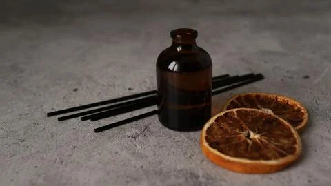 Citrus reed diffuser on dark background. Bottle, sticks and dry oranges Stock Photos