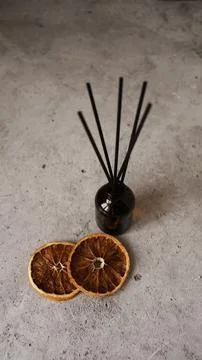 Citrus reed diffuser on dark background. Bottle, sticks and dry oranges Stock Photos