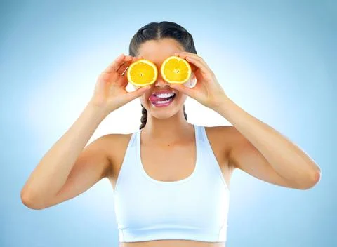 Citrusy silliness. Studio shot of a healthy young woman holding up oranges in Stock Photos