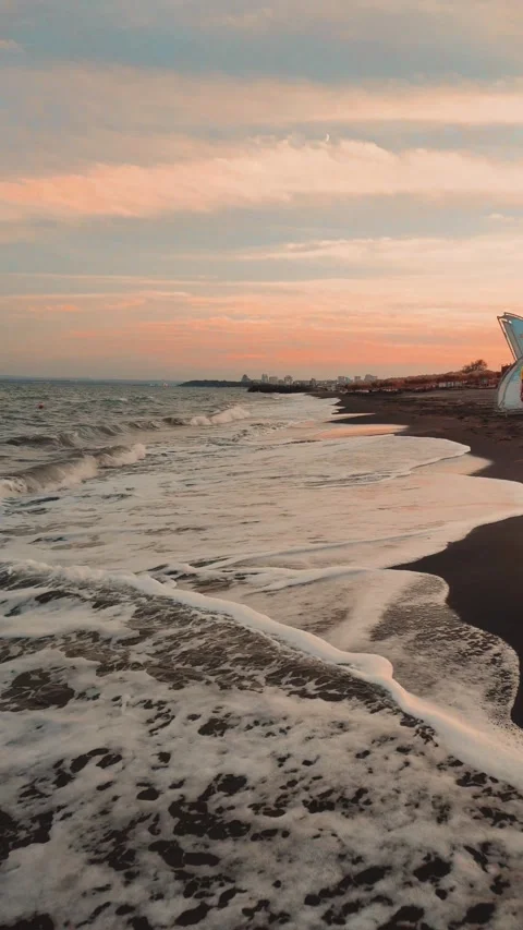 City Beach Sunset: Small Waves and Urban Horizon Stock Footage 284378437
